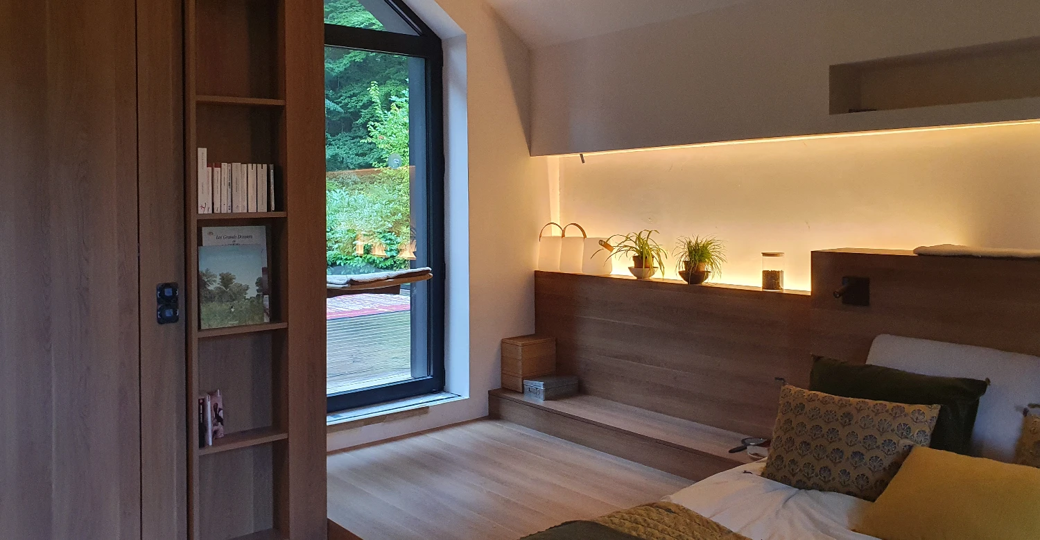 Agencement de chambre sur mesure avec tête de lit en bois Agencement intérieur sur mesure d’une chambre avec tête de lit en bois et éclairage indirect
