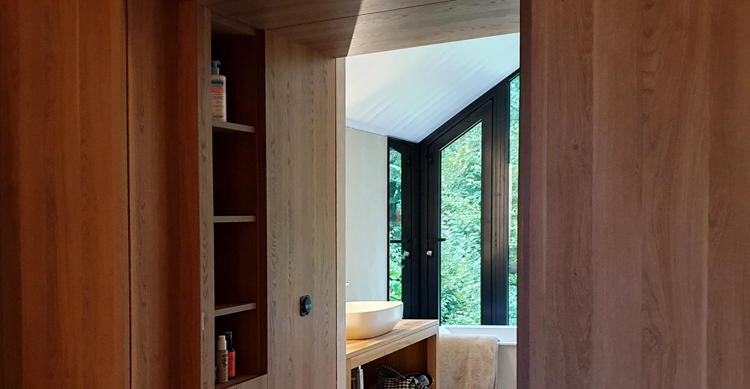 Agencement de couloir et rangements bois sur mesure Agencement intérieur sur mesure en bois avec rangements intégrés et passage vers salle de bain – projet près du lac d’Aiguebelette