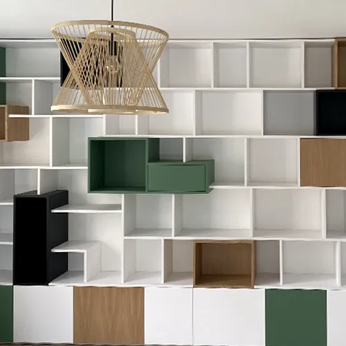 Bibliothèque murale sur mesure Bibliothèque murale sur mesure avec niches colorées intégrée dans un agencement intérieur