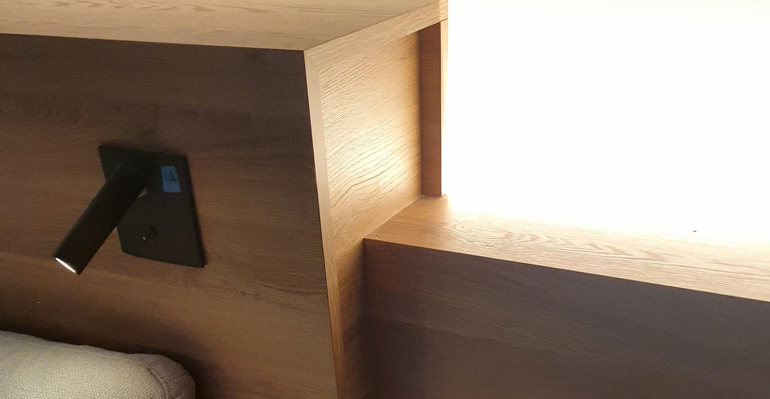 Tête de lit en bois avec éclairage indirect intégré Détail d’agencement sur mesure avec tête de lit en bois et éclairage indirect intégré dans une chambre