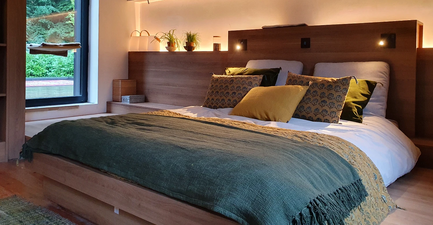Tête de lit en bois avec éclairage indirect Tête de lit en bois avec éclairage indirect intégré dans un agencement de chambre sur mesure