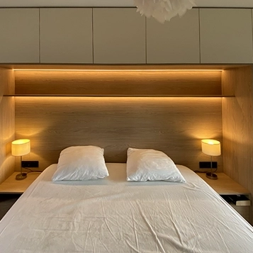 Pont de lit avec rangements et éclairage intégré dans une chambre réalisée sur mesure
